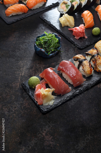 Sushi. Apetyczne, różnorodne sushi na kamiennym talerzu. Kompozycja na ciemnym tle.