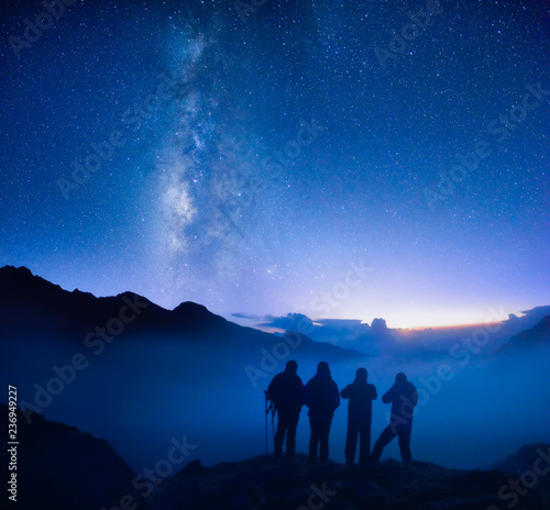 Group of travelers looking at the starry sky in the mountains.