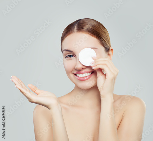 Papier peint Attractive woman cleaning her face with a cotton pad on white background