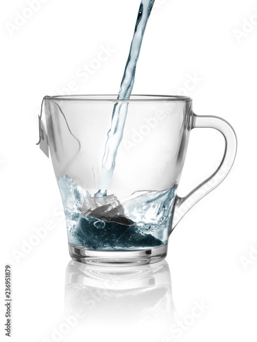 boiled water flows a stream from a teapot in a glass cup with a disposable bag of green tea