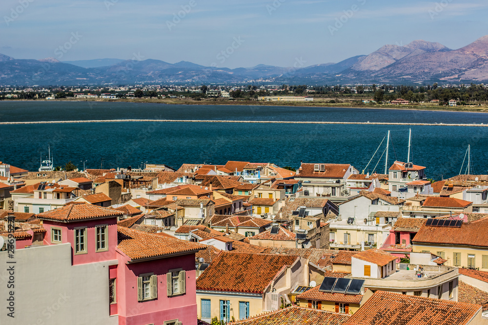 small south city in Mediterranean shore line waterfront view from above with shingles roof on tops and sea port bay and mountain country side horizon landscape on background 