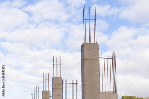 Baustelle mit gegossenen Betonstützen mit Armierungseisen vor blauem Himmel mit Wolken photo