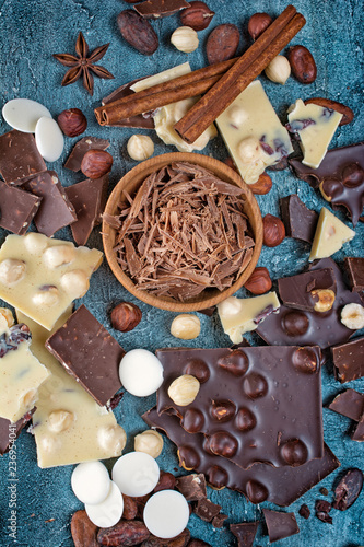 Top view of chocolate chips with pieces of dark and white bars with whole hazelnuts