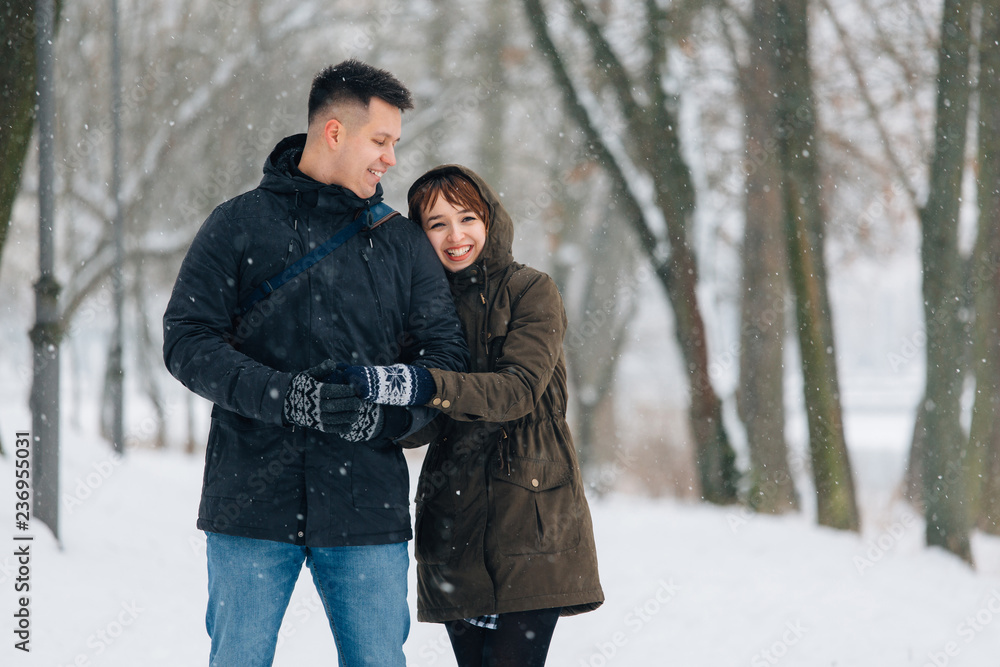 Winter portrait of young beautiful happy smiling couple outdoors. Christmas and winter holidays. Man and woman in snowy park Winter portrait of young beautiful happy smiling couple outdoors. Christmas and winter holidays. Man and woman in snowy park