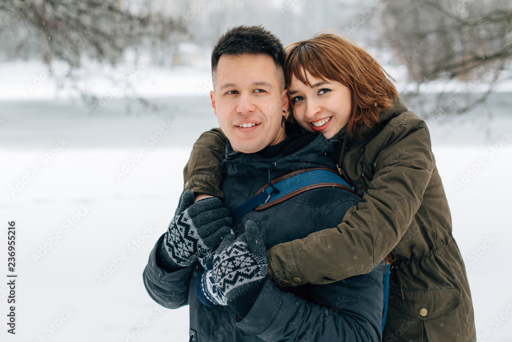 Winter portrait of young beautiful happy smiling couple outdoors. Christmas and winter holidays. Man and woman in snowy park Winter portrait of young beautiful happy smiling couple outdoors. Christmas and winter holidays. Man and woman in snowy park