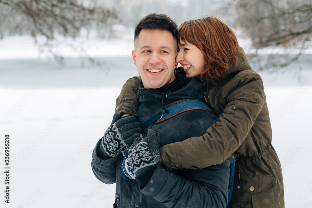 Winter portrait of young beautiful happy smiling couple outdoors. Christmas and winter holidays. Man and woman in snowy park Winter portrait of young beautiful happy smiling couple outdoors. Christmas and winter holidays. Man and woman in snowy park