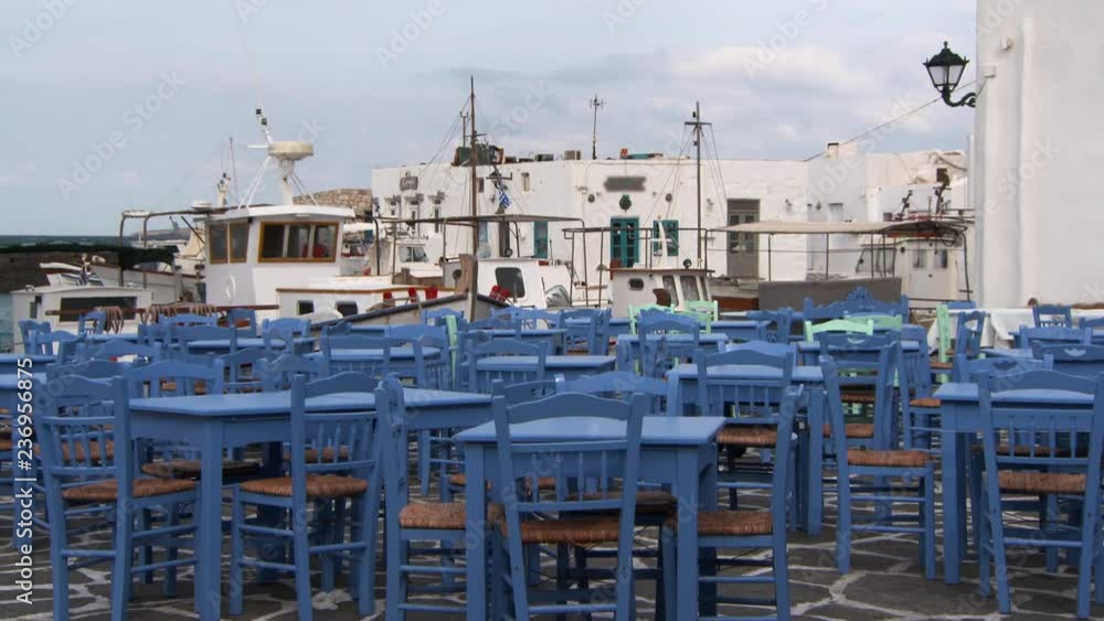 Lockdown: Outdoor Dining Area With Blue Tables and Chairs and Boats Rock Beyond Lockdown: Outdoor Dining Area With Blue Tables and Chairs and Boats Rock Beyond