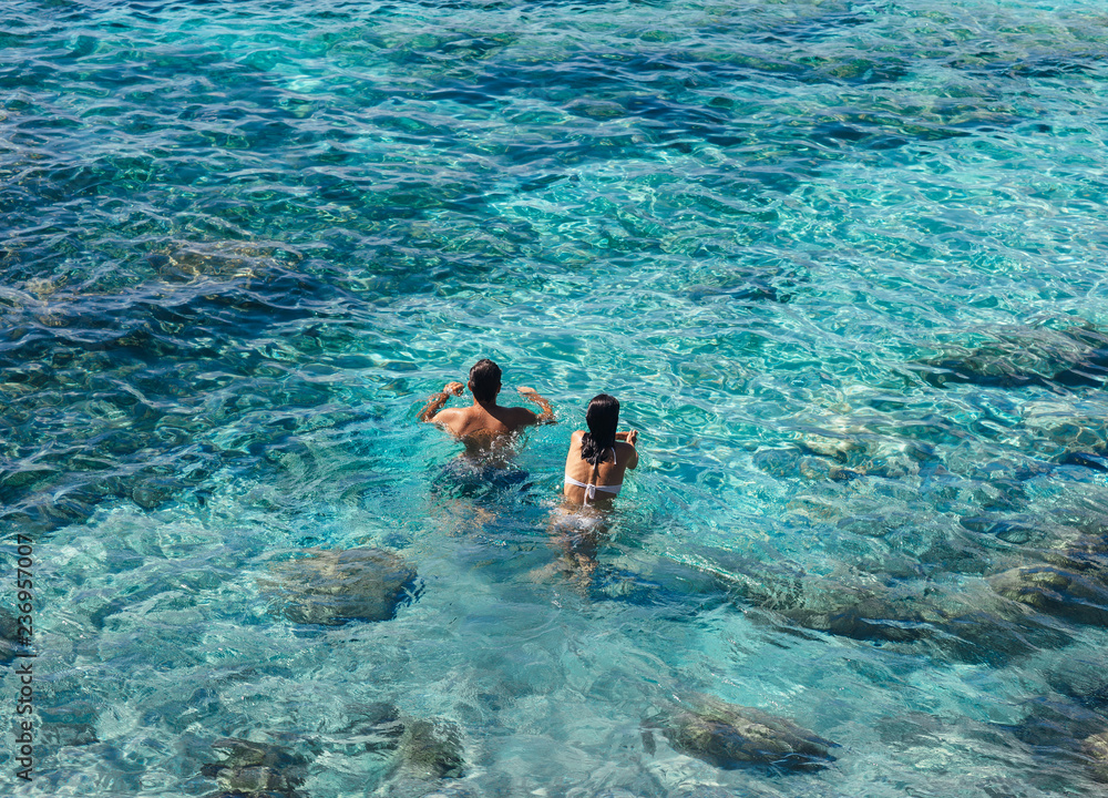Happy couple swimming in the transparent turquoise sea.
