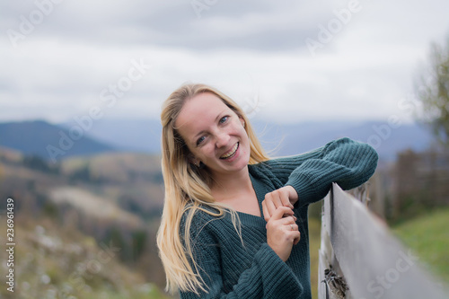Girl in the mountains. Blonde in the snowy mountains. Babe rejoices and shows the class. Portrait of a young woman