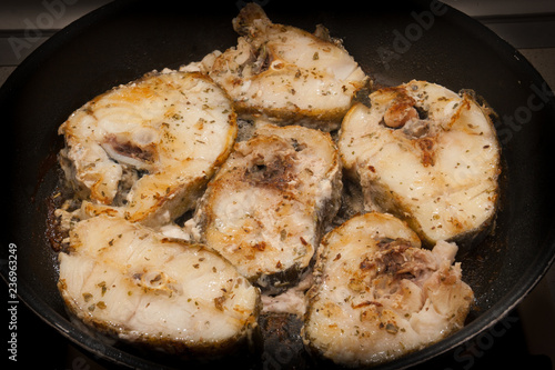 Canvas Print Fried cod fish in a pan with condiment and herbs