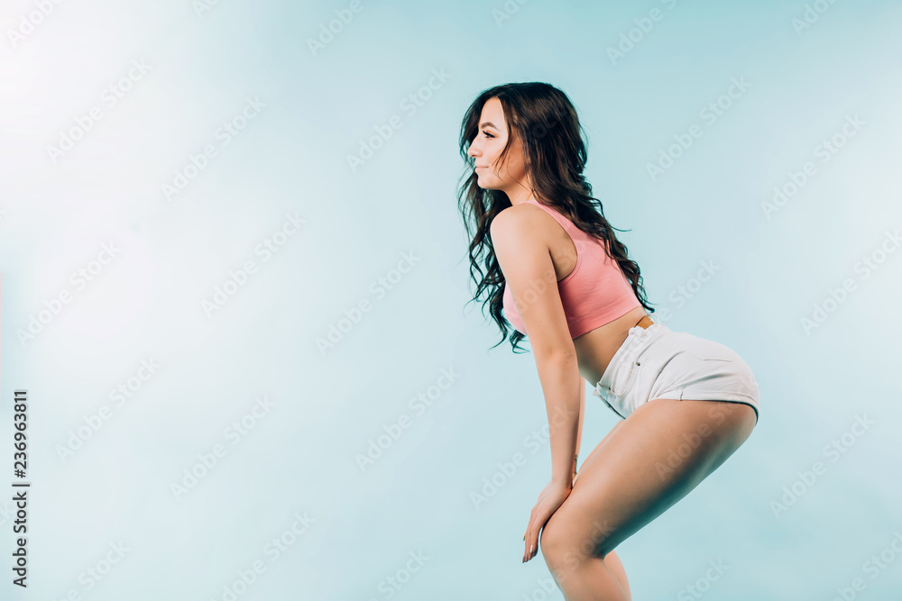 Young tall athletic women in blue, grey, brown standing behind each other.  Fitness girls posing on pink background. Stock Photo