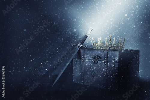 Fototapeta Naklejka Na Ścianę i Meble -  mysterious and magical image of old crown, wooden chest and sword over gothic black background. Medieval period concept.