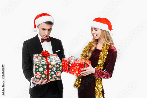 Happy couple of lovers, in Santa Claus hats with Christmas gifts in their hands.
