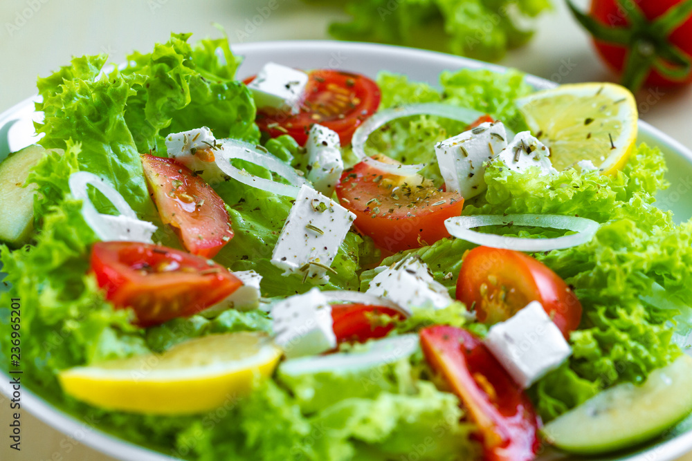 Fresh, healthy vegetable salad with feta cheese and lemon wedges in a plate. Healthy and right food. Diet Fresh, healthy vegetable salad with feta cheese and lemon wedges in a plate. Healthy and right food. Diet