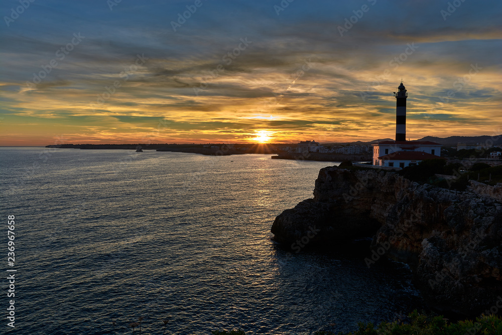 Lighthouse at sunset under a splendid sky of colors and a calm sea. Mediterranean sea in Spain. Baleares, Mallorca