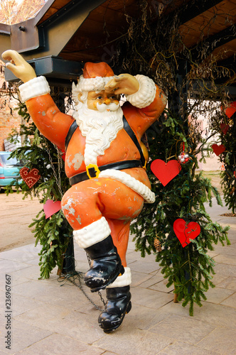 Funny grungy Santa Claus in hurry. Christmas decoration hanging outdoor in the city. France.