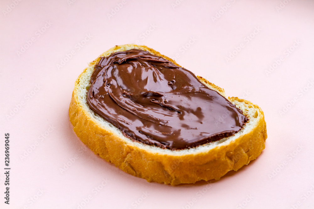 Piece of loaf with spread chocolate paste on a pink background. Sweet, nut butter with fresh bread for breakfast. Chocolate sandwich Piece of loaf with spread chocolate paste on a pink background. Sweet, nut butter with fresh bread for breakfast. Chocolate sandwich