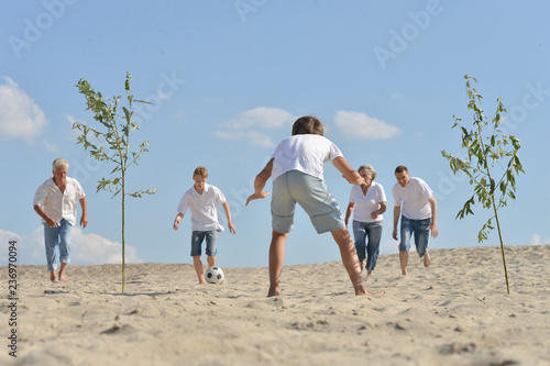 Happy family playing football on a beach in summer day