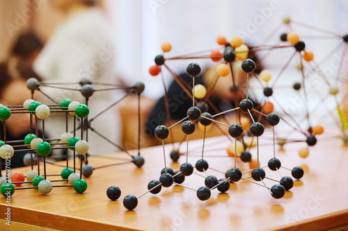 Students sit in the classroom and listen to a lecture in science. Plastic molecular educational model. Soft focus background image