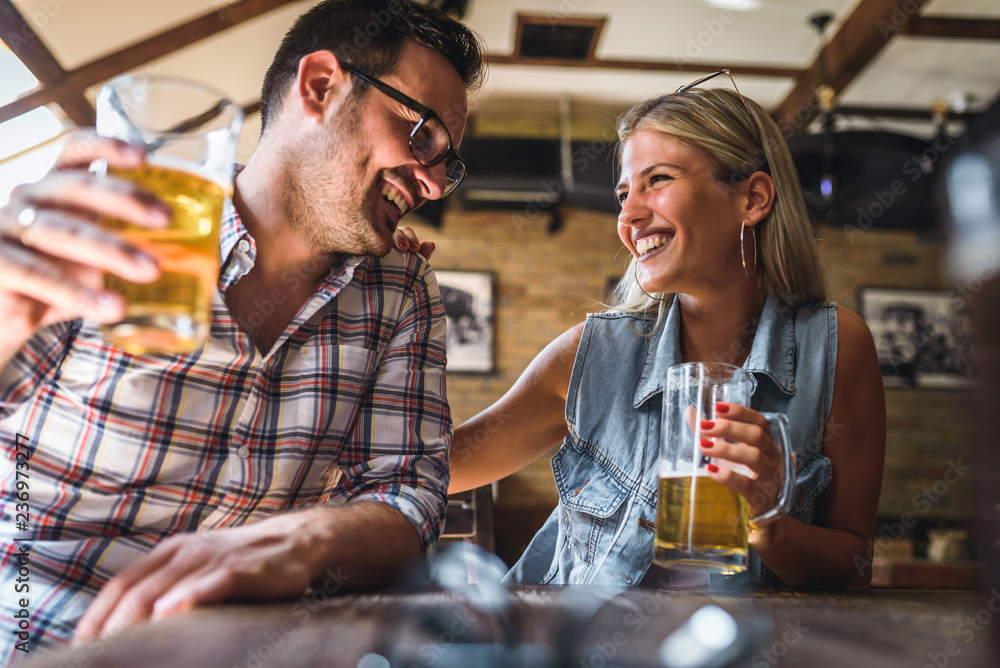 Young cheerful couple in the beer pub drinking and having good time Young cheerful couple in the beer pub drinking and having good time