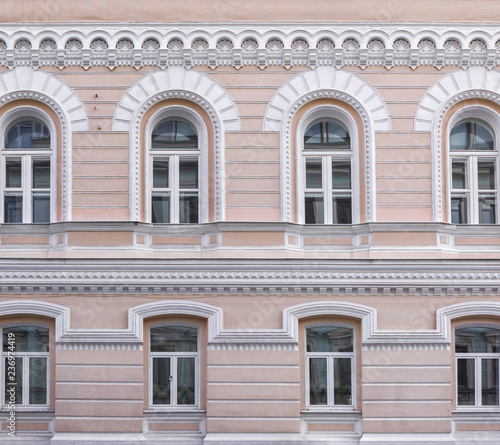 Vintage architecture classical facade building. openwork architectural decorations, arched windows. Front view close up.