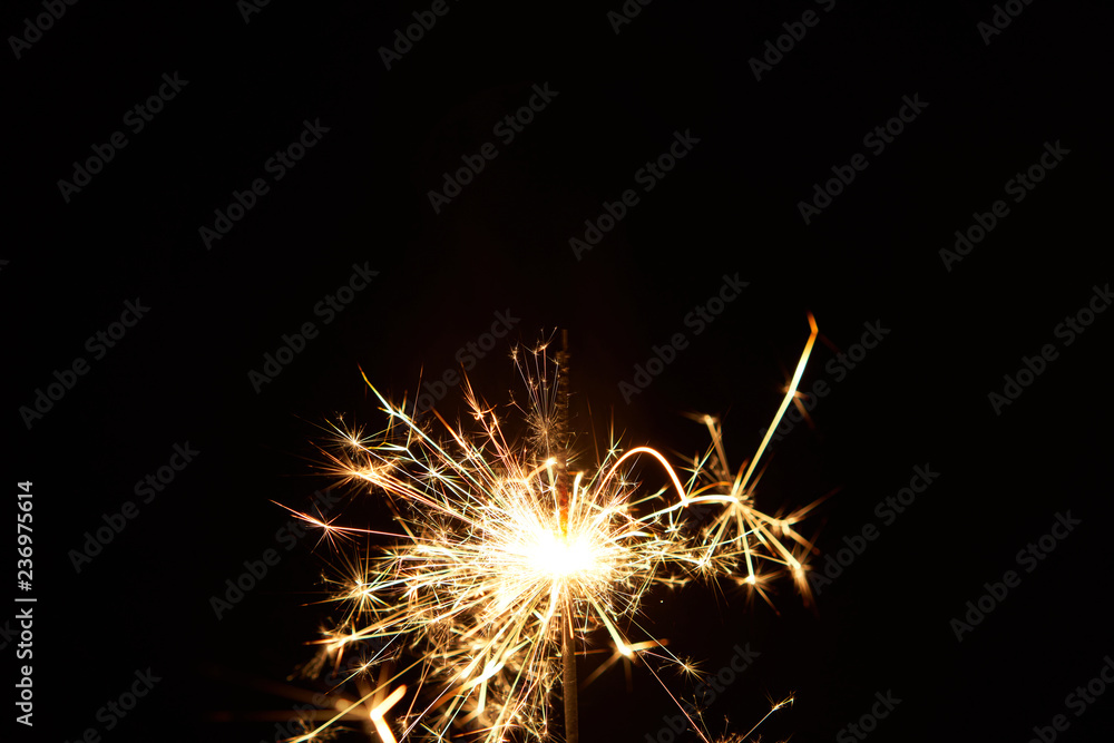 A burning sparkler on a black background isolated