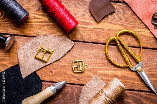 leather craft instruments on wooden background top view