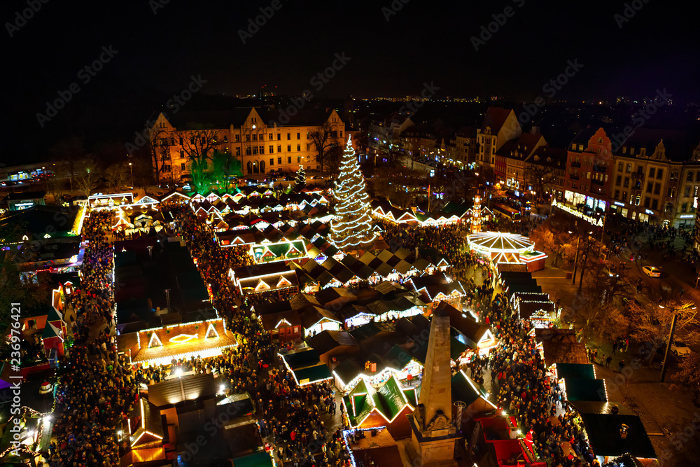 Naklejka premium Traditional Christmas market in Erfurt, Thuringia in Germany. With xmas tree, pyramide and sales and food stands on late evening or night.