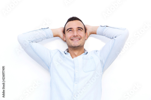 older guy smiling and looking up with hands behind head against shite background