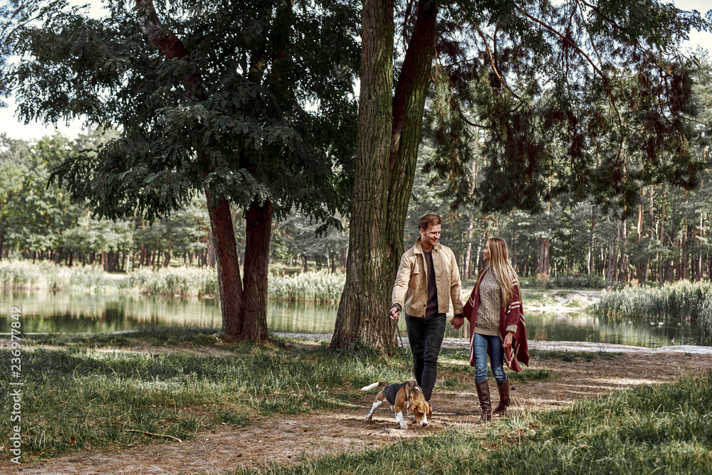 Fototapeta premium Young couple are walking with dog in forest
