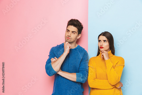 Pensive young couple standing isolated