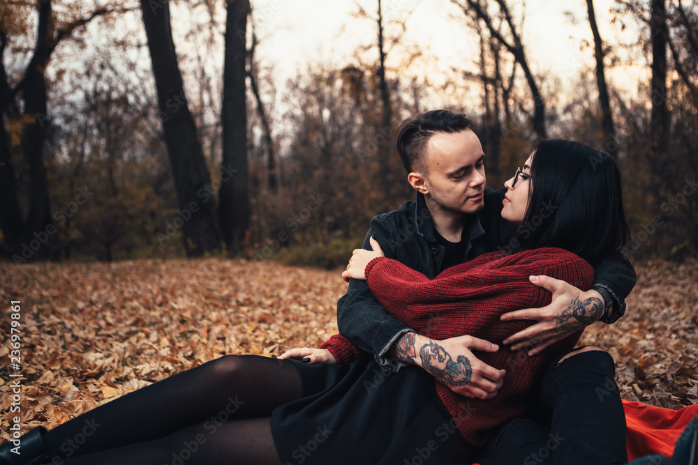 young man and young woman are sitting on a plaid in an autumn forest young man and young woman are sitting on a plaid in an autumn forest