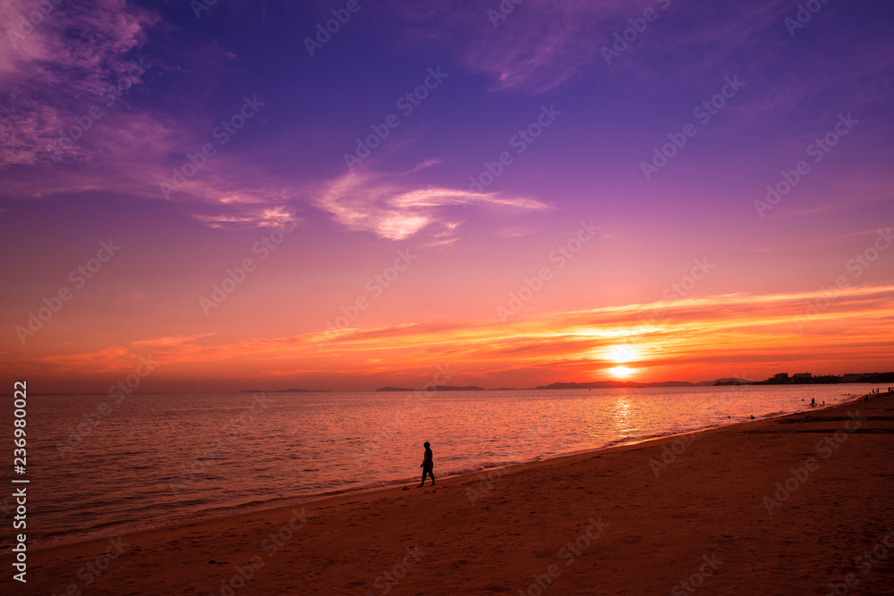 Silhouette tourist traveller relaxing walking on the beach in sunset with twilight beautiful sky