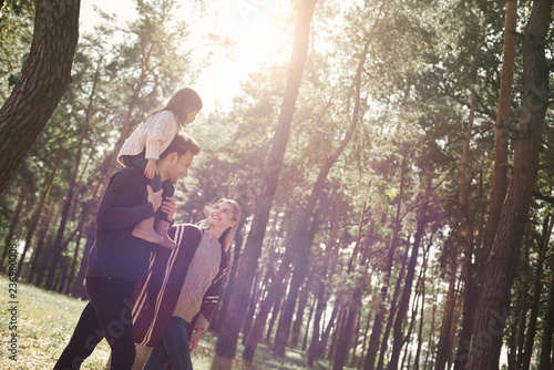 Young parents with little daughter in autumn forest. Side view