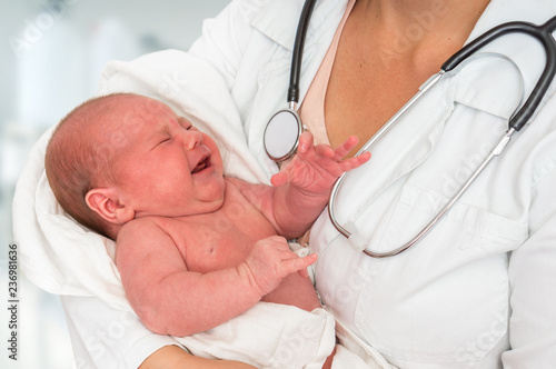 Pediatrician doctor is holding newborn baby in arms
