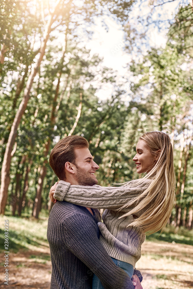 Fototapeta premium Young man holding his girlfriend on hands in autumn forest.