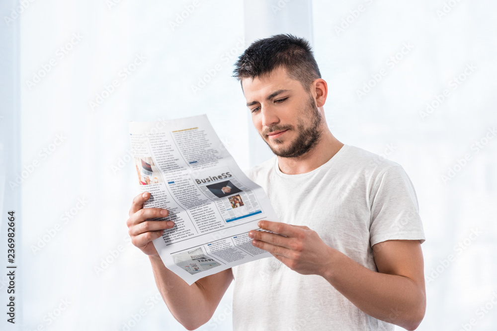 handsome man reading business newspaper in bedroom in morning at home handsome man reading business newspaper in bedroom in morning at home