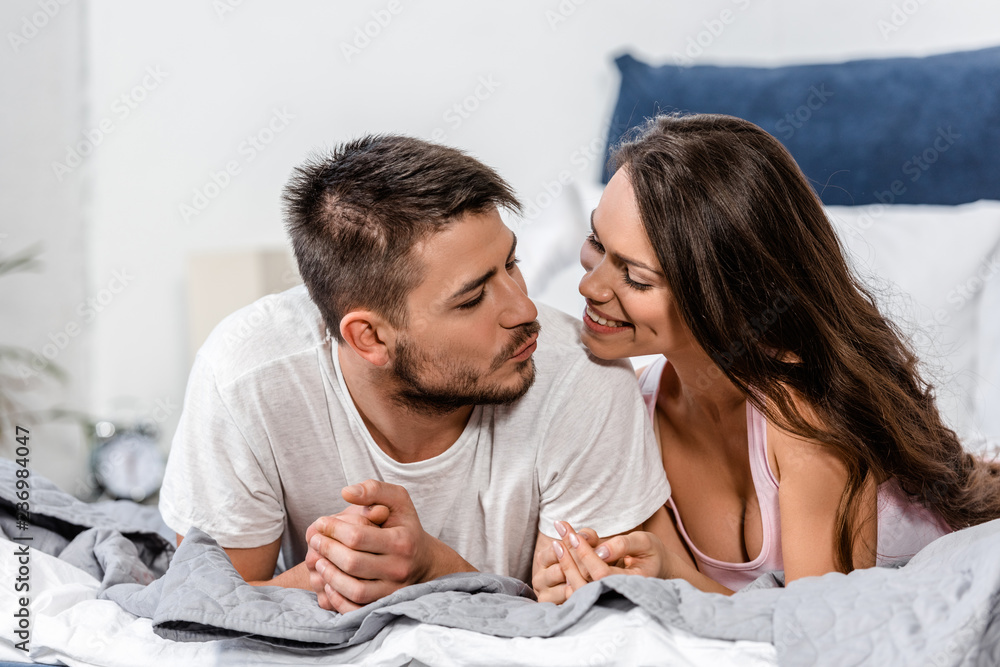 girlfriend and boyfriend in pajamas lying on bed and going to kiss in bedroom girlfriend and boyfriend in pajamas lying on bed and going to kiss in bedroom