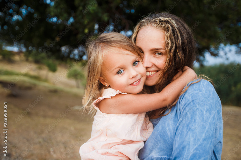 Сurly mother and child are hugging and having fun outdoor in nature Сurly mother and child are hugging and having fun outdoor in nature