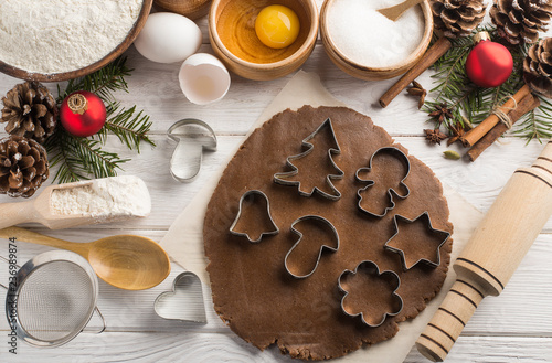Creative fresh Christmas biscuits with ingredients for baking on a wooden white background. Flat lay