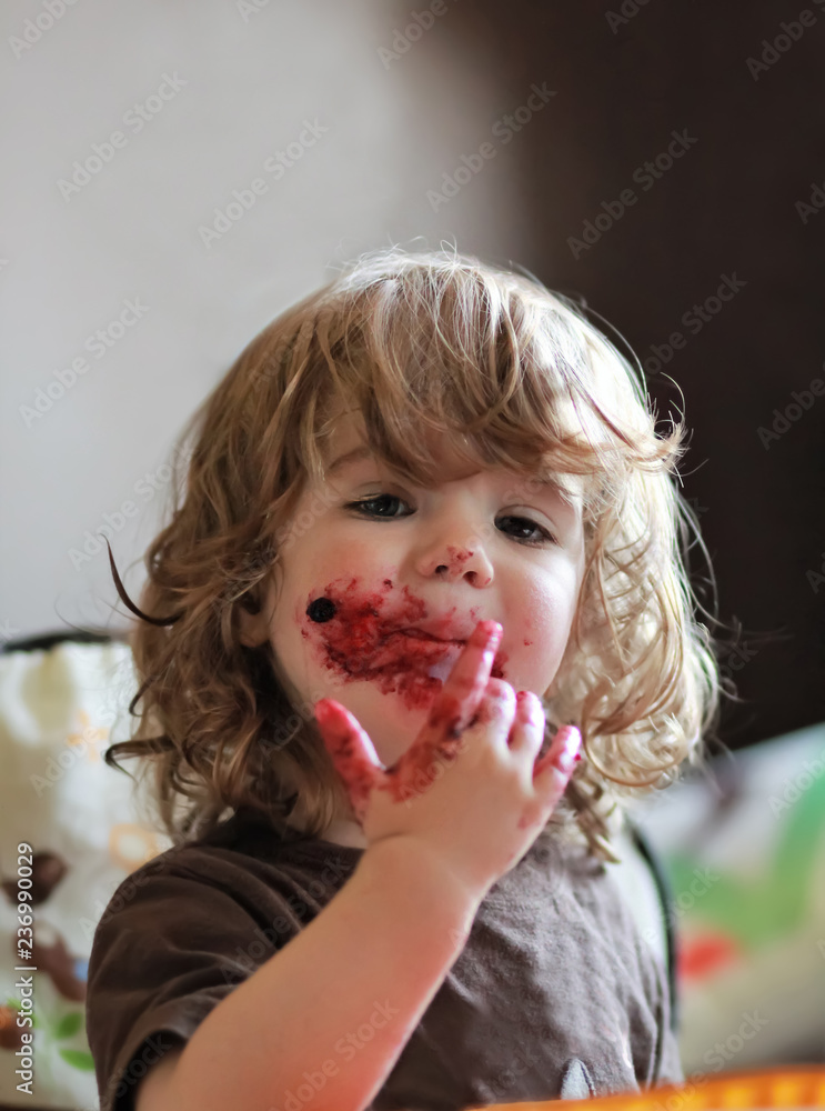 One year old baby girl eating delicious blueberry and black currant pie with her face dirty all over. One year old baby girl eating delicious blueberry and black currant pie with her face dirty all over.