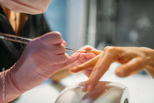 Beautician sticks the nails of female client photo