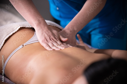 Massage session. A woman receiving a massage. Back massage. Pressing on the loin © KONSTANTIN SHISHKIN