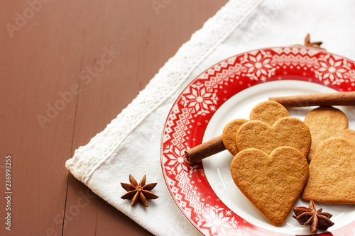 Gingerbread heart-shaped cookies with cinnamon sticks and anise stars on a red plate
