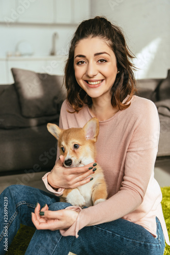 laughing woman with cute welsh corgi pembroke at home