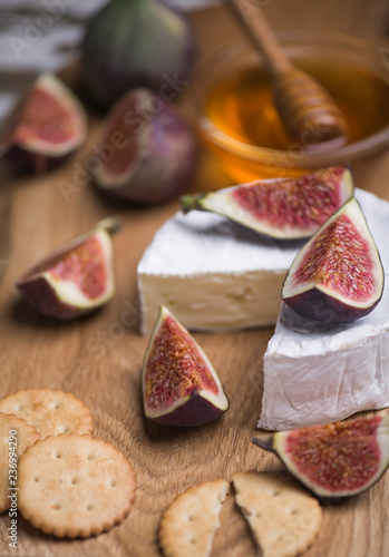 Flowers honey with fresh cheese and salt kcracker, ripe figs on a wooden board.