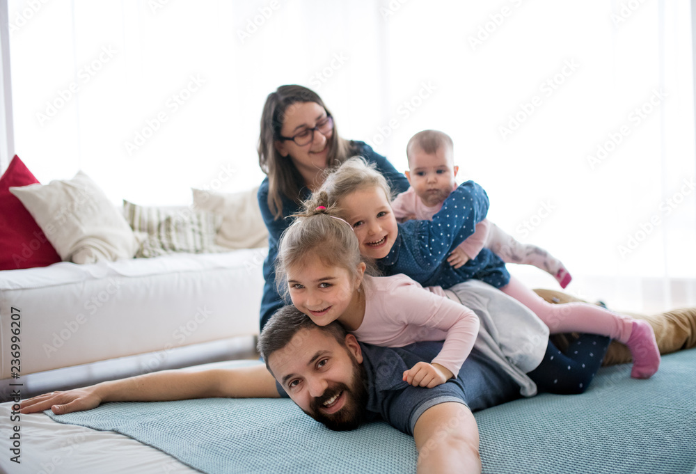 A portrait of young family with small children lying on floor indoors.