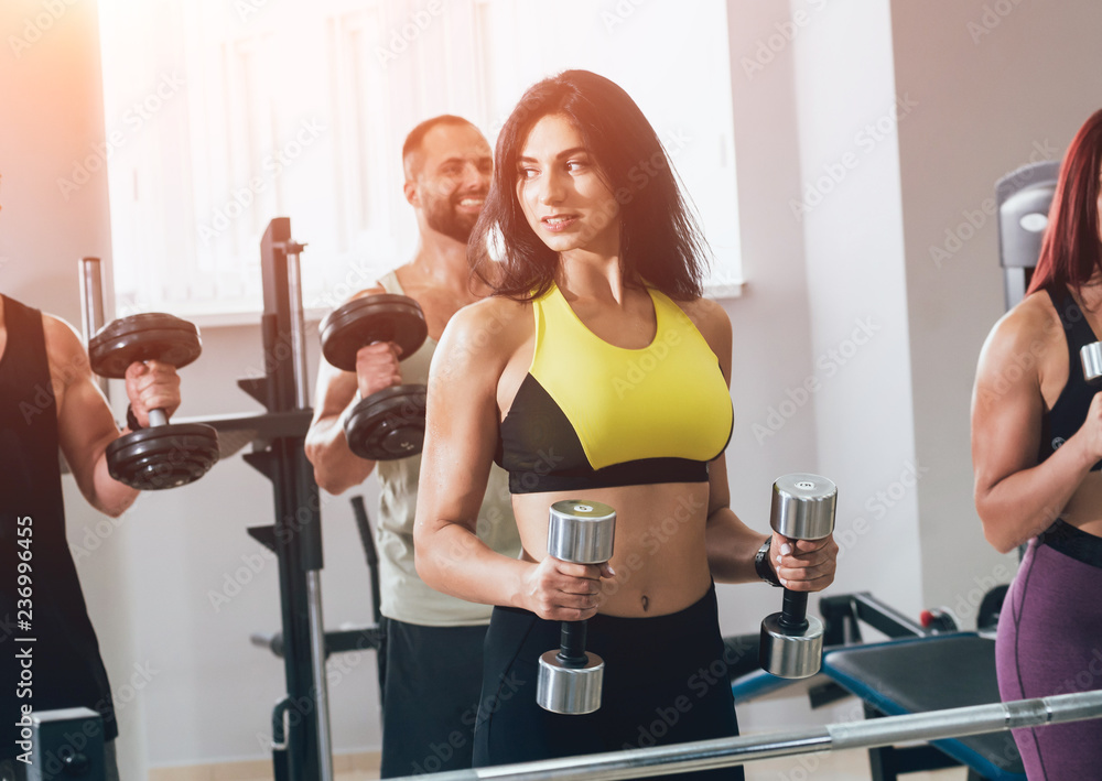 Fototapeta premium Group of athletic young peoples making exercise at the gym. Young men and women with muscular body.