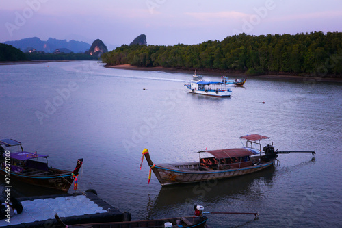 long boat in sea run to port with mangrove forest sea and sunset purple sky