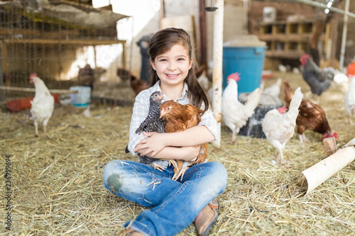 Fotografie Cute Little Girl Embracing Chickens At Farm